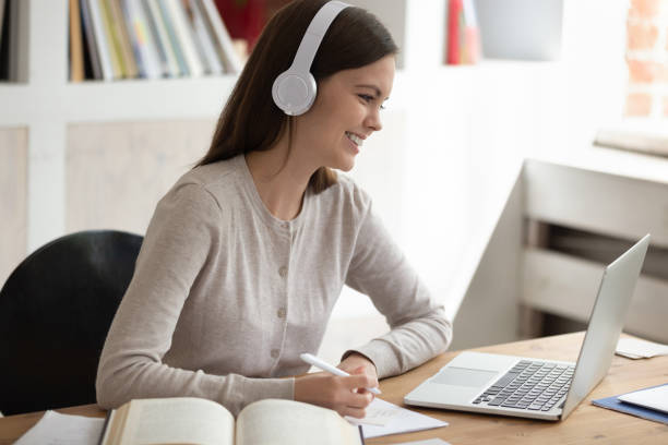 istock Smiling young female student wearing headset watching educational video. 1179756380