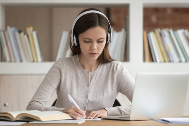 istock Concentrated female student studying, wearing wireless headphones. 1179756382