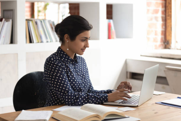 istock Focused confident indian female student studying with books and computer. 1179756397