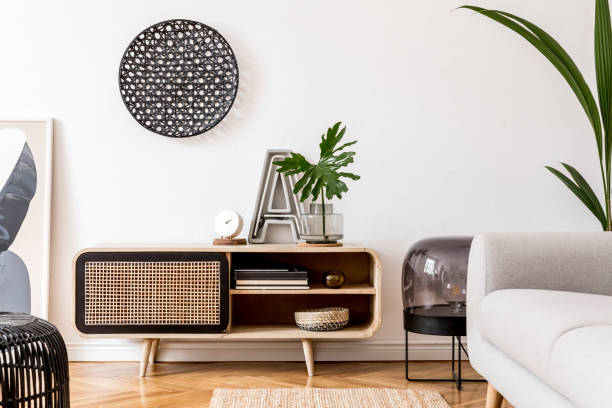 istock Stylish scandinavian living room interior with gray sofa, black lamp, design commode, tropical plants, sculpture, books and personal accessories. Design home decor. Template. 1179759993