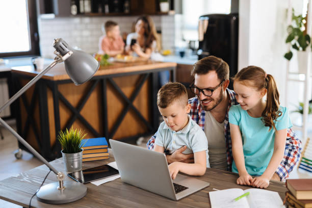 istock Father with daughter and son on his lap using laptop at home 1179760991