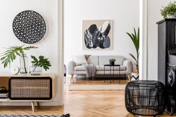 istock Modern scandinavian interior design of open space with stylish wooden commode, gray sofa, black piano, rattan table, plant, tropical leaf and elegant personal accessories. Stylish home decor. Template 1179761229