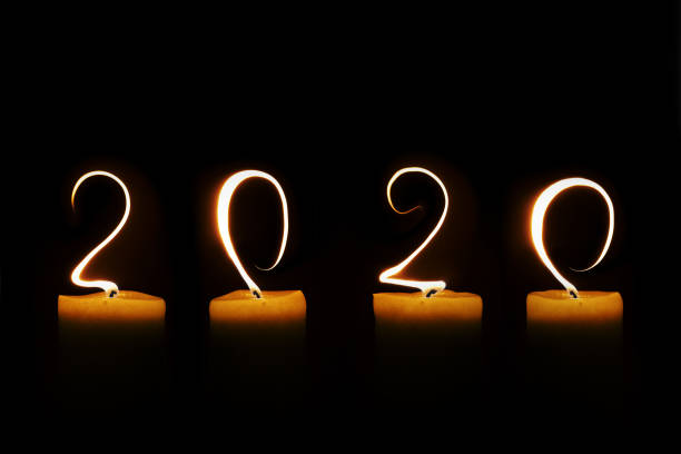 istock 2020 written with candle flames on black background, greeting card 1179761261