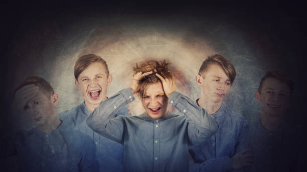 Desperate teenage boy, hands to head, suffer split emotions into different inner personalities. Multipolar mental health disorder. Schizophrenia psychiatric disease. Dementia reactions mood change. Desperate teenage boy, hands to head, suffer split emotions into different inner personalities. Multipolar mental health disorder. Schizophrenia psychiatric disease. Dementia reactions mood change. janus head stock pictures, royalty-free photos & images