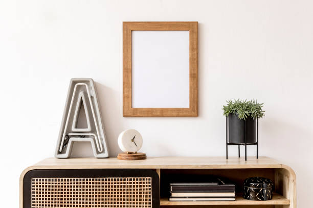 istock Modern interior design with mock up photo frame, wooden commode, books, plant, big letter, white clock and elegant accessories. Stylish home decor. Template. Mockup ready to use. 1179761730