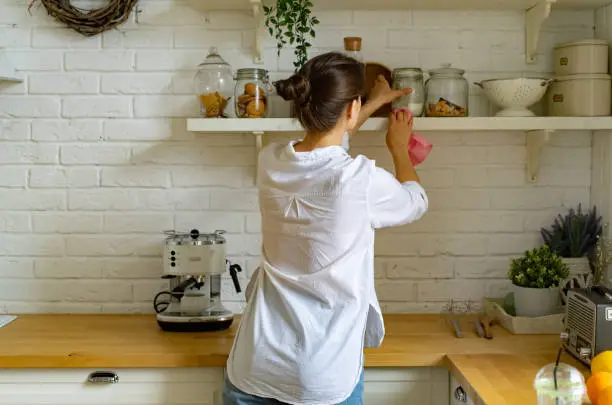 Photo of Young woman cleaning dust at the kitchen