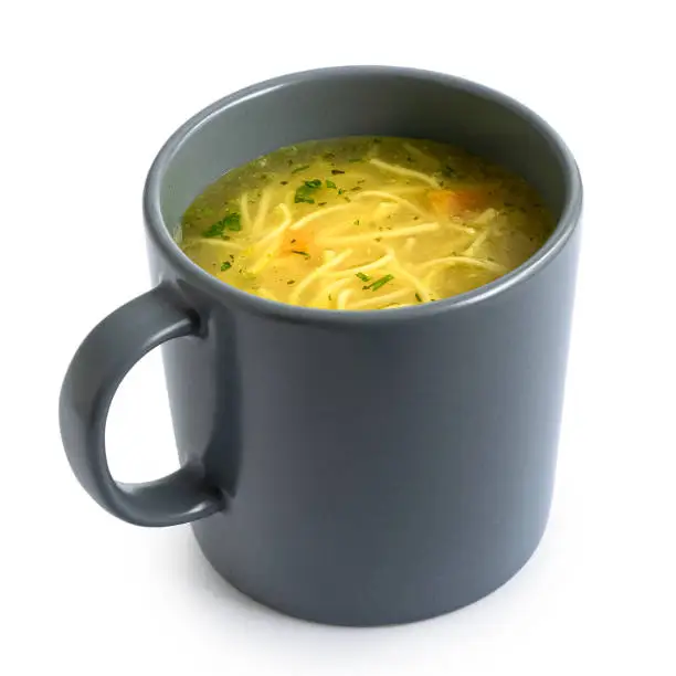 Instant chicken noodle soup in a grey ceramic mug isolated on white.