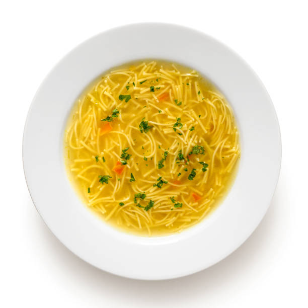 istock Instant chicken noodle soup in a white ceramic soup plate isolated on white. Top view. Chopped parsley. 1179762481