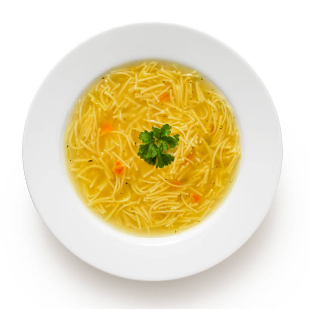 istock Instant chicken noodle soup in a white ceramic soup plate isolated on white. Top view. Parsley garnish. 1179762497