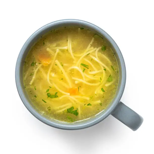 Instant chicken noodle soup in a grey ceramic mug isolated on white. Top view.