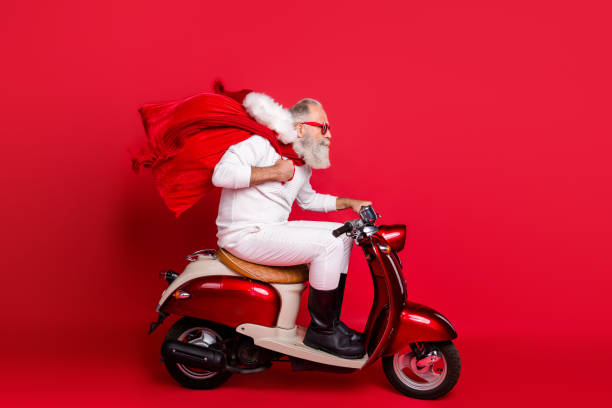 profile side view of nice bearded gray-haired saint nicholas riding motor delivering carrying desirable purchase things december wintertime isolated on bright vivid shine red background - active seniors enjoyment driveway vitality imagens e fotografias de stock