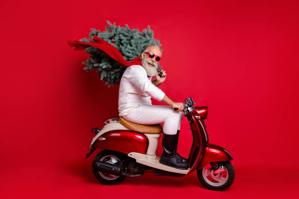 full size profile side photo of cheerful pensioner on motorcycle carry fir tree travel hurry to christmas time wear sweater pants isolated, over red background - active seniors enjoyment driveway vitality imagens e fotografias de stock