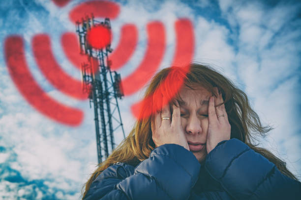 Woman is holding her head near the 5G BTS stock photo