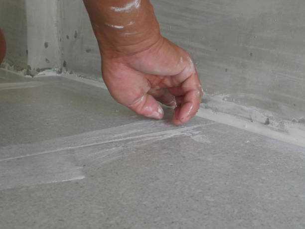 istock A construction worker's hand puting tile grout on to the laid ceramic tiles on the floor - tiling work 1179766042