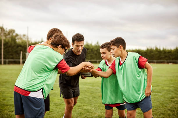 istock Coach and soccer players stacking hands on field 1179770178