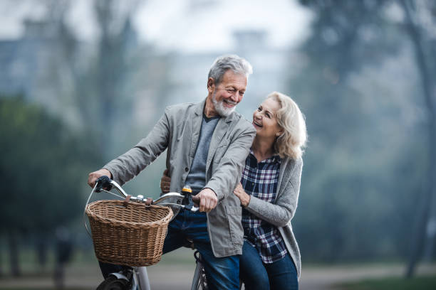 自然の中でサイクリングしながら話す幸せなシニアカップル。 - retirement mature couple couple bicycle ストックフォトと画像