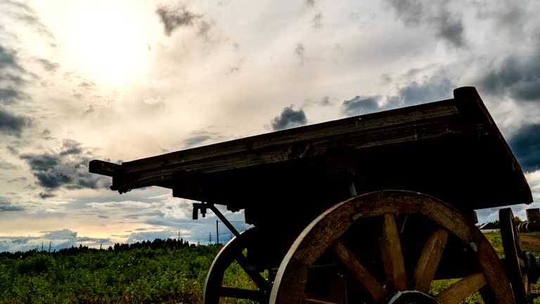 Antique wooden cart standing alone in a field, beautiful autumn landscape, hyperlapse, time lapse, heavy autumn sky