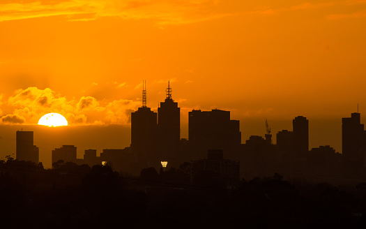 Big golden sun setting behind Melbourne city skyline
