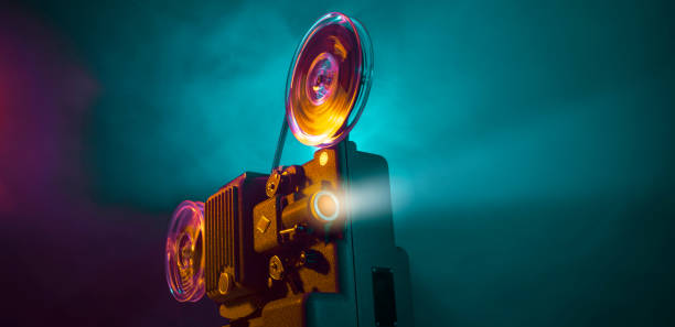 Vintage film projector and film screening Vintage old fashioned projector in a dark room projecting a film, cinematography concept vintage movie projector stock pictures, royalty-free photos & images