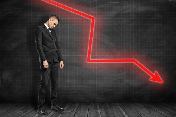 istock Sad businessman with red arrow going down on black background 1179772517