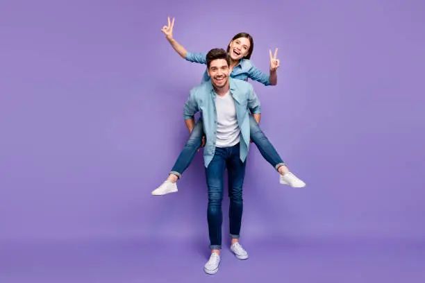 Full size photo of romantic couple with brunet hair redhair enjoy date honeymoon, hug piggyback make v-signs wear trendy stylish outfit isolated over violet color background