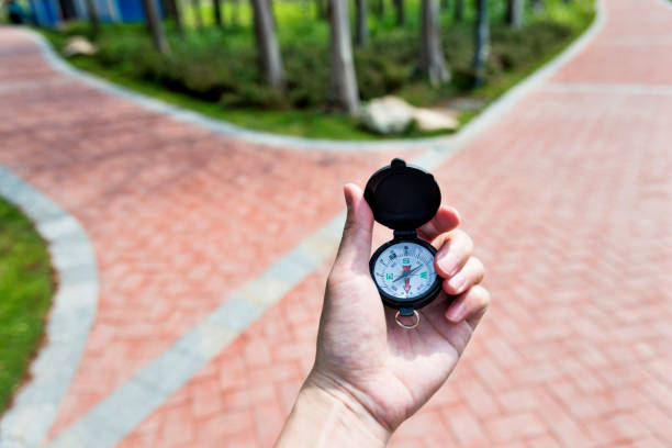 Man hand holding a compass on the forked road.