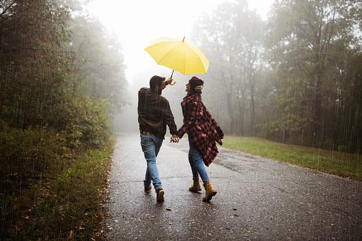 Romantic rainy day out in the Amsterdam streets for a diverse tourist couple made up of an alternative brunette female and a curly transgender woman