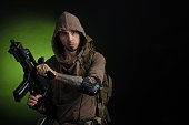 man Stalker with a gun with an optical sight and a backpack on a dark background with emotions looking, aiming, watching, sneaking