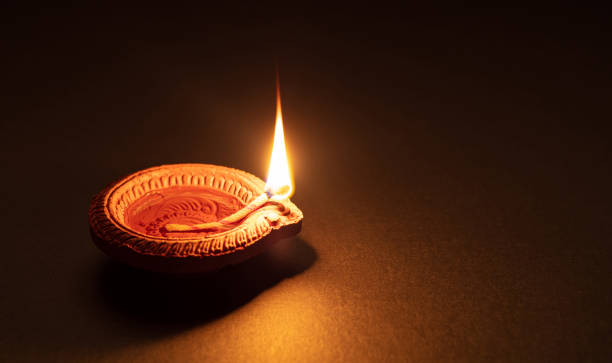 Diwali, Hindu festival of lights celebration. Diya oil lamp against dark background, Happy Diwali. Clay diya candle illuminated in Dipavali, Hindu festival of lights. Traditional oil lamp on dark background, copy space. clay oil lamp stock pictures, royalty-free photos & images