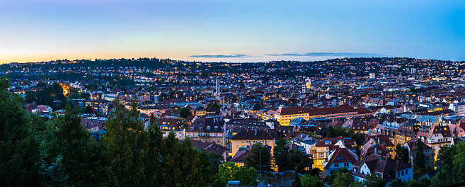 Germany, XXL panorama of sunset sky over urban cityscape of stuttgart city houses and roofs, aerial view from above over illuminated skyline in summertime