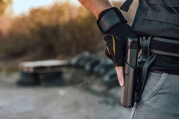 image de plan rapproché d'un homme retenant le pistolet de main dans l'étui sur la ceinture. - gun men holding handgun photos et images de collection