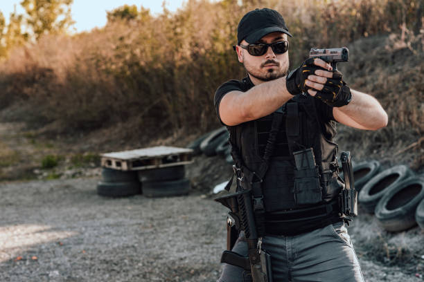 istock Young security contractor shooting a hand gun, portrait, copy space. 1179779865