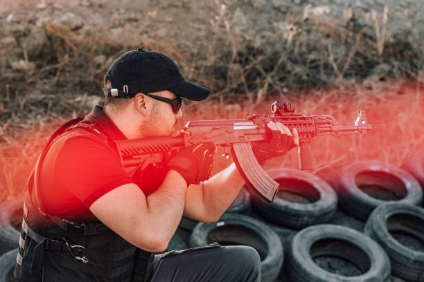 istock Man aiming at a target and shooting rifle outdoors, side view. 1179779869