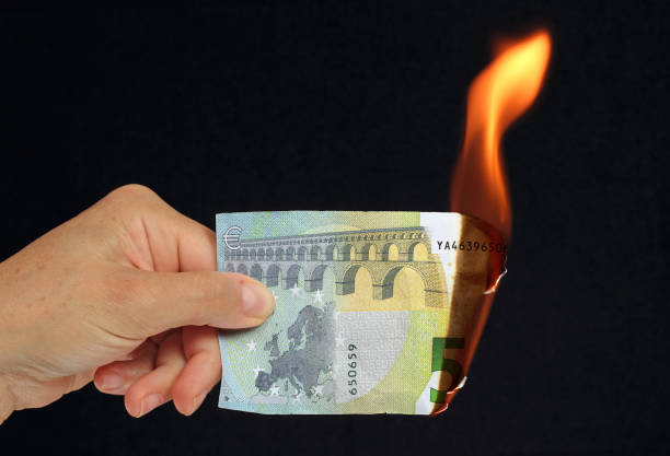 istock hand holding a burning euro bank note 1179780988