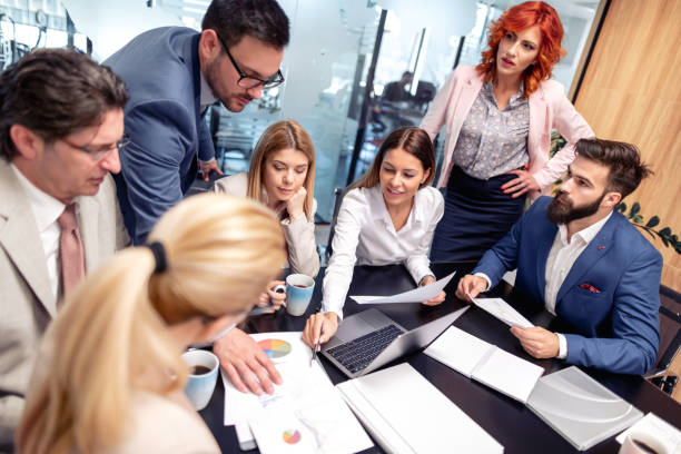 istock Group of business people working and communicating while sitting at the office desk 1179781802