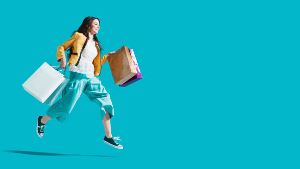 Cheerful happy woman enjoying shopping Cheerful happy woman enjoying shopping: she is carrying shopping bags and running to get the latest offers at the shopping center shopaholic stock pictures, royalty-free photos & images