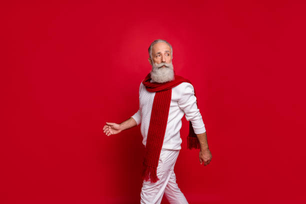 istock Portrait of classy retired man walking looking wearing white pullover pants trousers isolated over red background 1179786294