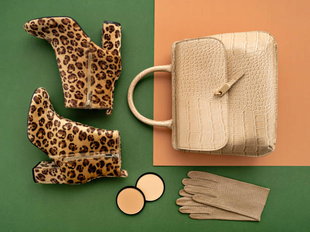 Fashion blogger products. Top view on a pair of trendy leopard print boots, crocodile crossbody bag, leather gloves, and makeup products. Flat lay of feminine trendy accessories in green and beige tones. dress shoe photos stock pictures, royalty-free photos & images