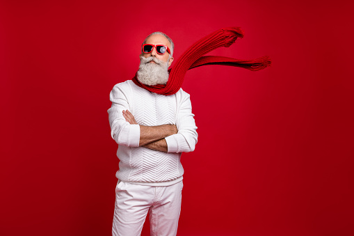 Trendy grey-haired superhero santa wear sun specs knitted clothes, isolated red background