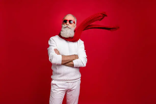 Photo of Trendy grey-haired superhero santa wear sun specs knitted clothes isolated red background