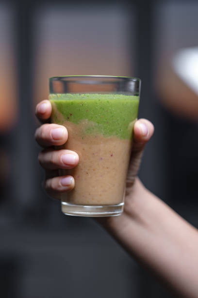 istock Glass cup with smoothie in hand. Drinking green healthy smoothie concept. 1179787073