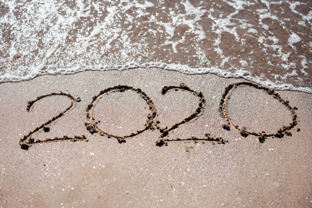 istock 2020 written in beach sand and washed by a wave 1179790347