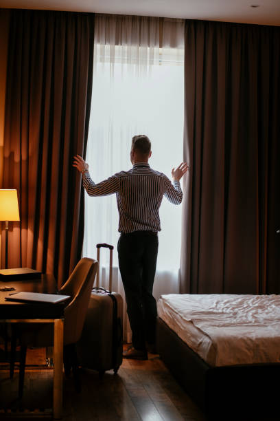istock Businessman looking through hotel room window 1179793488