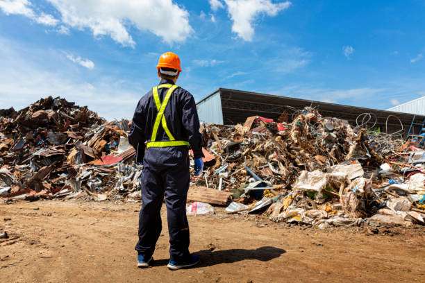 Engineer and recycle. Engineers standing in recycling center. back view of Male foreman wearing protective equipments and holding tablet and looking at  Recyclable material. stock photo