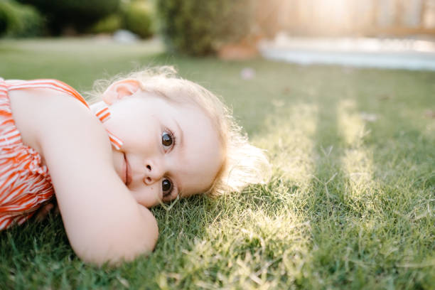 istock Happy Smiling Little Girl Lying On Grass 1179796410