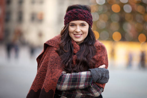 Beautiful joyful woman portrait in a city. Smiling  girl wearing warm clothes and hat  in winter or autumn stock photo