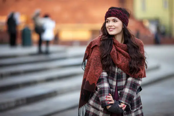 Photo of Beautiful joyful woman portrait in a city. Smiling  girl wearing warm clothes and hat  in winter or autumn