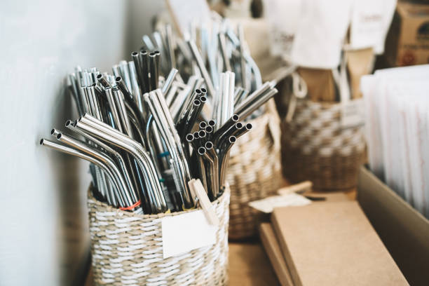 Metallic reusable straws in zero waste shop. Metallic stainless steel reusable straws on background with other goods in plastic free grocery store. Details of product assortment in zero waste shop. Alternative shopping at local small businesses local products stock pictures, royalty-free photos & images