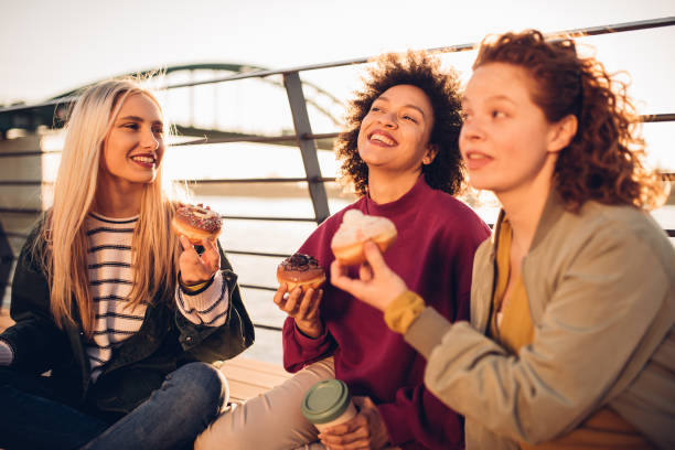 istock Girls laughing and eating donuts 1179798936