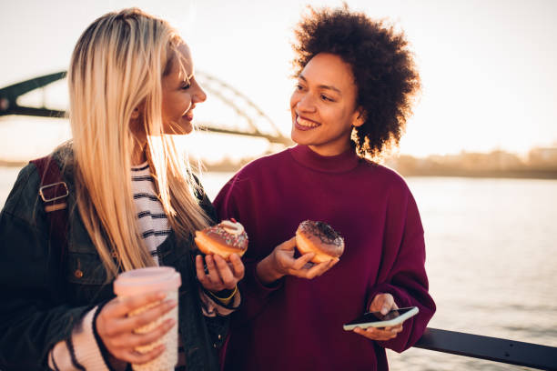 istock Two girls eating donuts and talking 1179798940